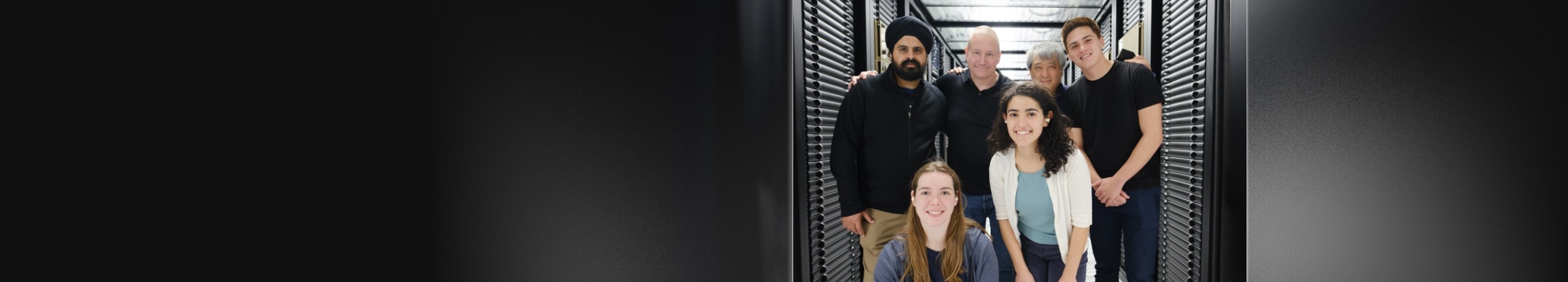 An image of a group of professionals standing next to each other in a data center.